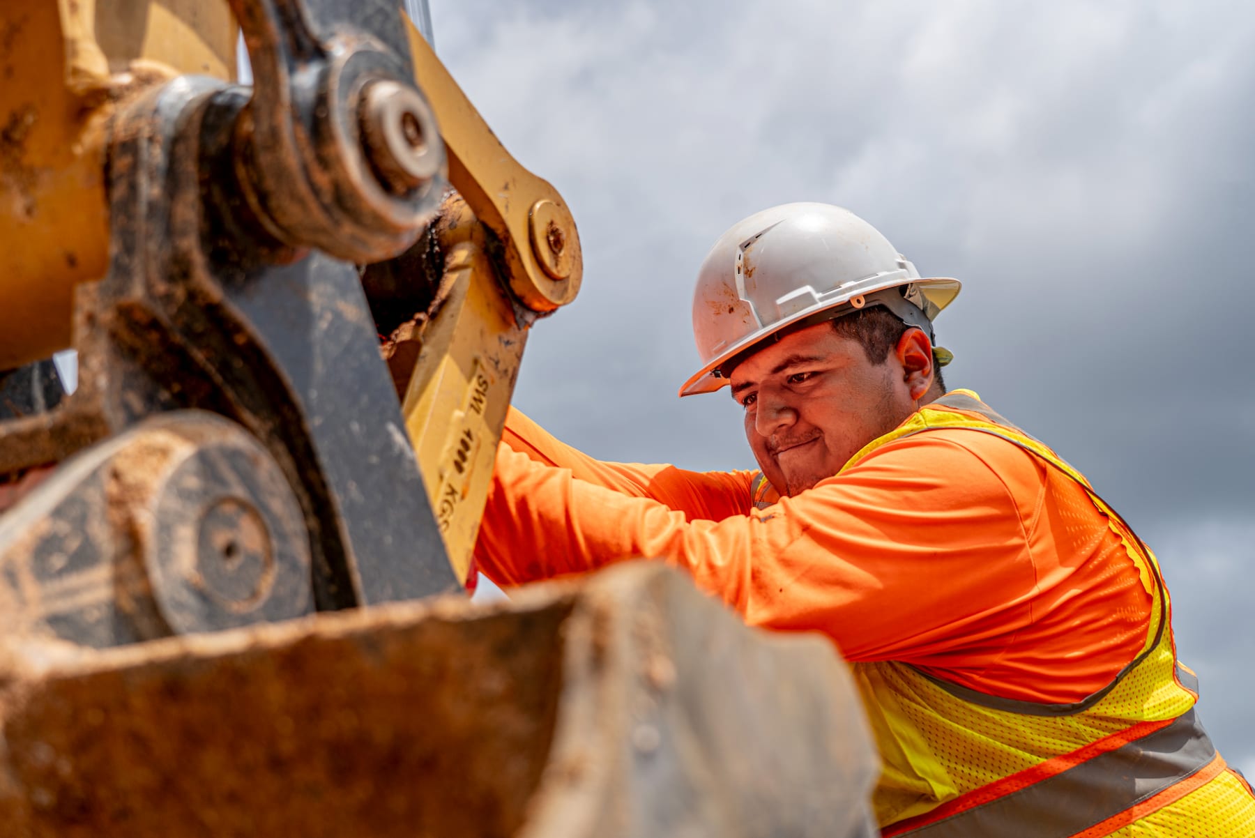 A worker at the bucket of a tracked excavator